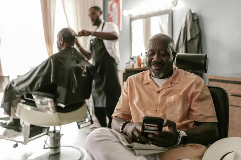 afroamerican old man at bareshop booking visit in best barber booking app
