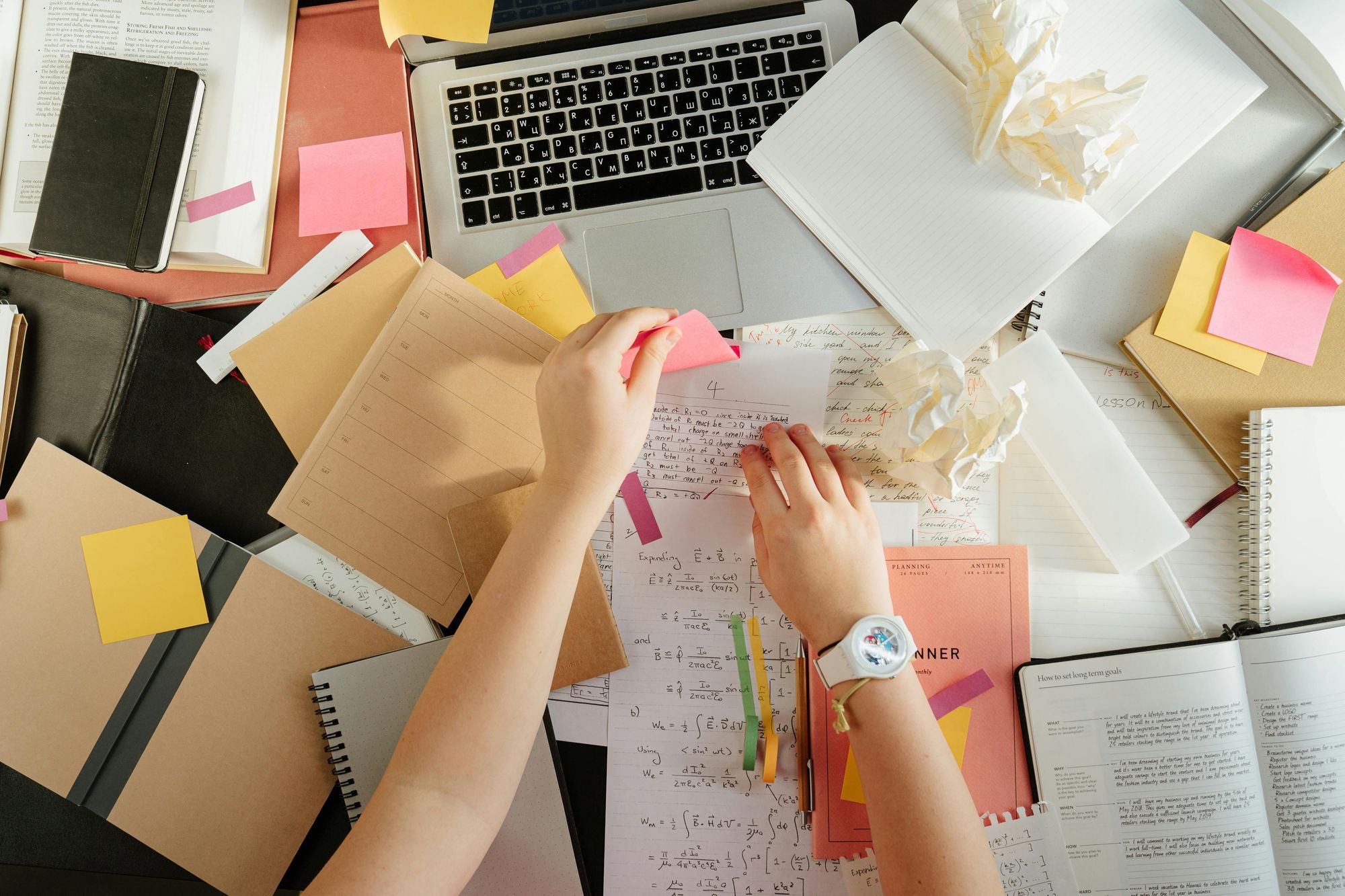 Teacher preparing school schedule with sticky notes and papers making mess on a desk