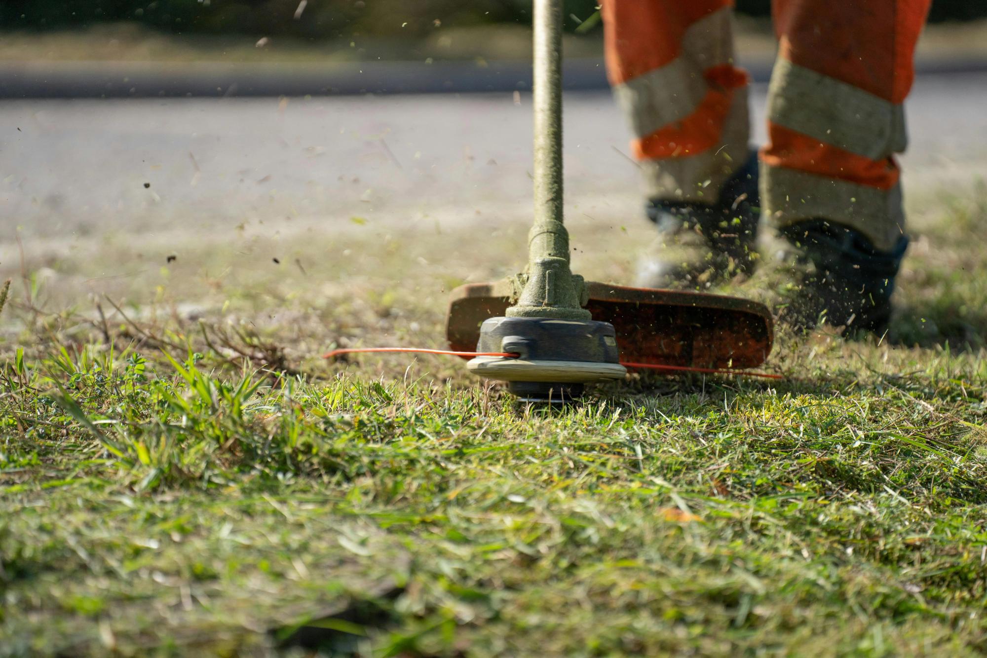 A lawn care specialist using a string trimmer to cut grass