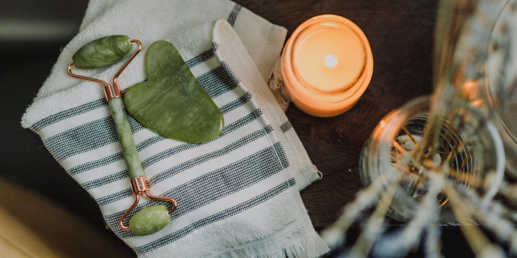 Jade roller and gua sha by candle on towel demonstrating day spa cancellation policy with automatic reminders and a rescheduling link.