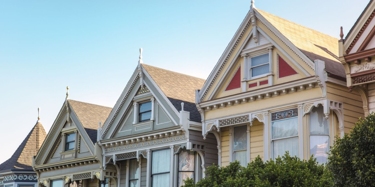 Row of colorful Victorian-style homes with ornate trim under a clear sky