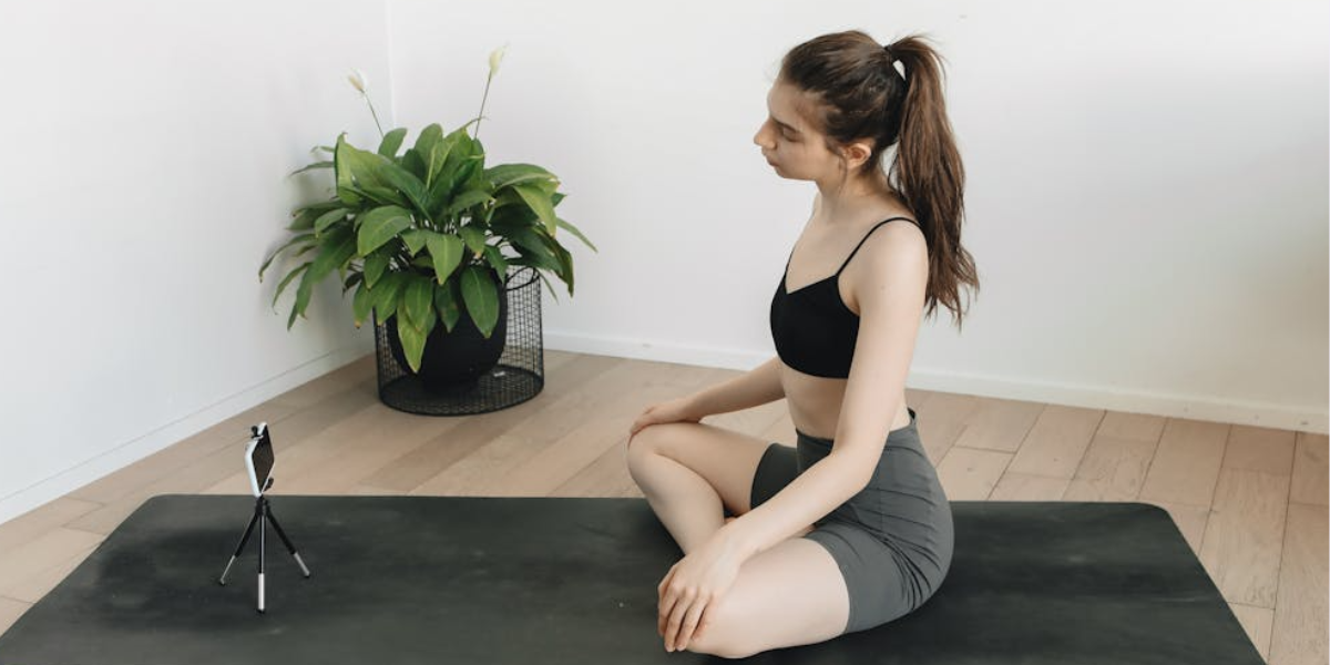 Female on yoga mat using streaming equipment